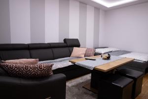 a living room with a black couch and a table at Apartament Kopernik in Wadowice