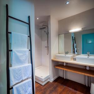 ein Badezimmer mit einem Waschbecken, einem Spiegel und Handtüchern in der Unterkunft Lodge Coco in Deshaies