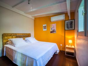 a bedroom with a white bed and an orange wall at Lodge Coco in Deshaies