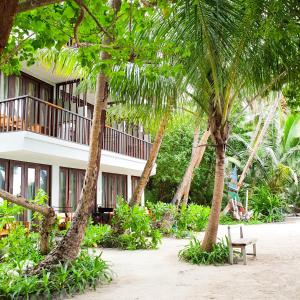 a resort with palm trees in front of a building at Thundi Sea View in Fulidhoo