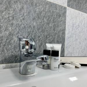 a sink with a faucet and other products on it at Bastau Hotel in Almaty