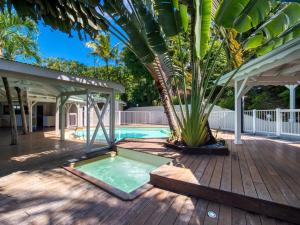 - une piscine sur une terrasse en bois avec un palmier dans l'établissement Lodge Coco, à Deshaies