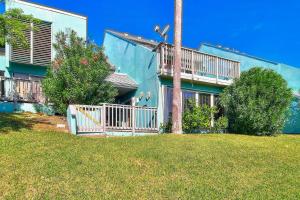 a blue house with a balcony and a yard at Puente Vista in Corpus Christi
