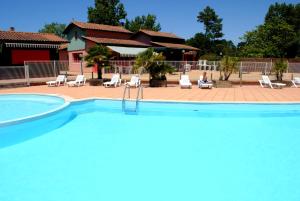 una grande piscina con persone sedute in un resort di Résidence Néméa Les Rives de Saint Brice ad Arès