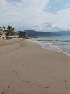 uma praia arenosa com o oceano e palmeiras em El Sunset Hostel em Puerto Vallarta