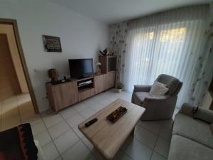 sala de estar con TV, sofá y mesa de centro en Ferienwohnung Lorenz en Oberhausen