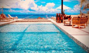a swimming pool with chairs and a view of the ocean at Singular Joy Downtown Residences in Playa del Carmen