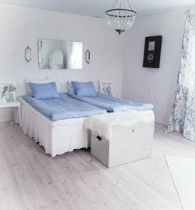 Dormitorio blanco con cama con almohadas azules en Höhällets Lantliga Rum, en Värnamo