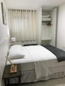 um quarto com uma grande cama branca e uma mesa em Apartamento Completo Jatiúca em Maceió