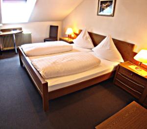 a bedroom with a large bed with white sheets and pillows at Hotel Gasthof Herderich in Schlüsselfeld