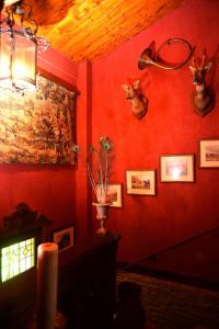een kamer met een rode muur met hertenkoppen erop bij La Minauderie in Écully