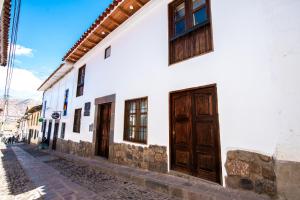 un edificio blanco con puertas de madera en una calle en Posada San Blas en Cuzco