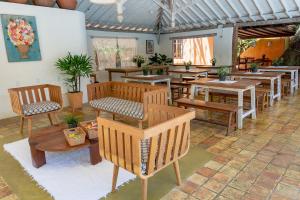 un restaurante con bancos de madera y mesas en una habitación en Pousada Erva Doce, en Arraial d'Ajuda