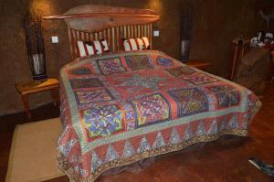 a bed with a colorful blanket on top of it at Antbear Eco Lodge Drakensberg in Emhubeni