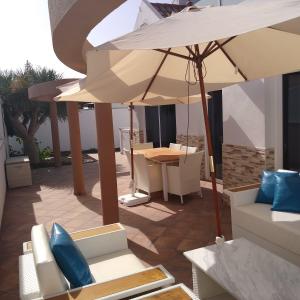 a patio with a table and an umbrella and chairs at Villa maravillosa in San Bartolomé de Tirajana
