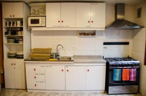 a kitchen with white cabinets and a sink and a stove at El Patagónico Hostel in Puerto Natales +11 photos