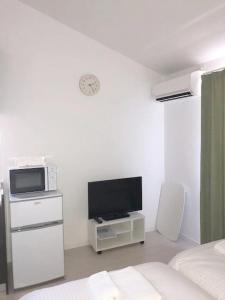 a bedroom with a bed and a tv and a microwave at ラ・マーレ福津海岸通り201 in Tsuyazaki