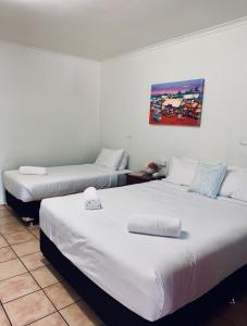 2 camas en una habitación con paredes blancas en Roebuck Bay Hotel en Broome