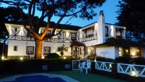 een groot wit huis met een boom ervoor bij Hosteria Actinia in Villa Gesell