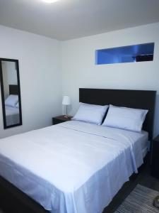 sypialnia z białym łóżkiem i lustrem w obiekcie Montreal Olympic Parc w Montrealu