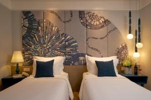 two beds sitting next to each other in a hotel room at Sofiana My Khe Hotel & Spa- Rooftop Pool Bar in Danang