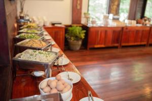 a buffet line with dishes of food and eggs at E-Outfitting Vang Thong Hotel in Luang Prabang