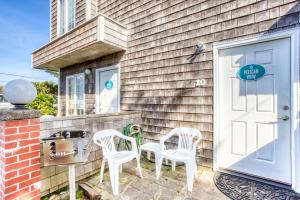 a pair of white chairs sitting outside of a house at Beaches Inn | Pelicans View Cottage in Cannon Beach