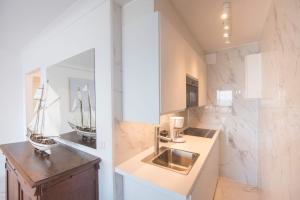 ein Badezimmer mit einem Waschbecken und einer Theke mit einem Spiegel in der Unterkunft Studio Hof ter zee II in Ostende