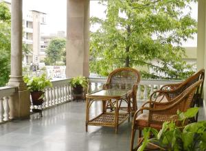 a table and chairs on a balcony with trees at Tara Niwas in Jaipur