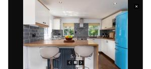 uma cozinha com armários brancos e um frigorífico azul em Cae Cwnws em Conwy
