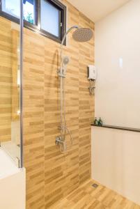 a shower in a bathroom with a wooden wall at Aonang Eco Villa - SHA Extra Plus in Ao Nang Beach
