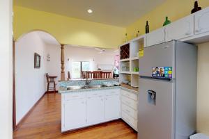 a kitchen with white cabinets and a refrigerator at Princesa Angienelle in Caye Caulker