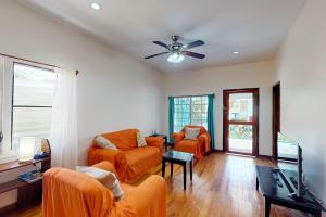 a living room with two couches and a ceiling fan at Princesa Angienelle in Caye Caulker
