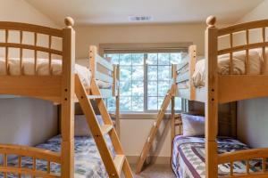 a bunk room with three bunk beds and a window at Alderhill in Shaver Lake