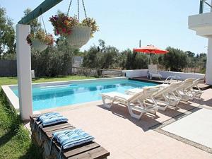 a swimming pool with lounge chairs and an umbrella at TEO-VILLA-1, private pool, sea and golf in Afantou