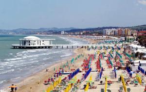 a beach with many colorful beach chairs and umbrellas at Appartamento nel Verde sul Mare di Senigallia in Senigallia