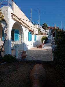 a white building with blue windows and a staircase at Beautiful Island house with sea view in Spiliazéza