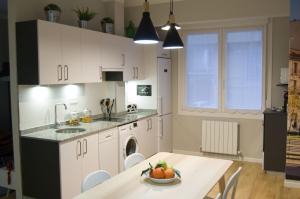 a kitchen with white cabinets and a table with a bowl of fruit at Markelenea - Bilbao – Casco Viejo – Parking – WIFI Gratis in Bilbao