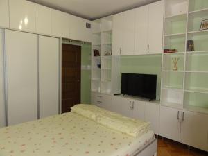 ソフィアにあるApartment SOFIA LUX TOP CENTERの白いキャビネット、ベッド、テレビが備わるベッドルーム1室が備わります。 +2枚の写真