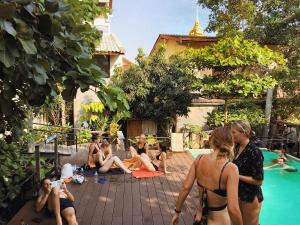 un grupo de personas sentadas alrededor de una piscina en Here Hostel Bangkok en Bangkok