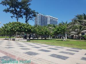 a park with palm trees and a tall building at SeaSala Hotel in Vung Tau