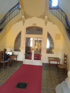 a person sitting at a table in a room with a red carpet at Studio à font romeu grand hôtel in Font-Romeu-Odeillo-Via
