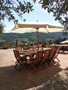 VILLA IL TRUFOLO في Pratolino: طاولة وكراسي خشبية مع مظلة