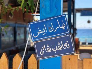 a blue sign with arabic writing on it at Salerno Dormitory in Dahab