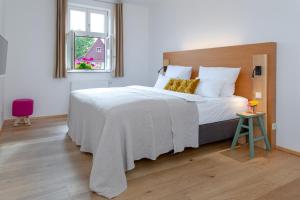Schlafzimmer mit einem großen weißen Bett mit einem Kopfteil aus Holz in der Unterkunft hezelhof hotel in Dinkelsbühl