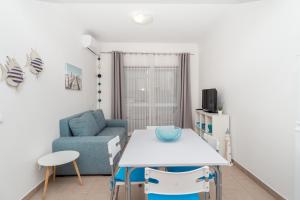 sala de estar con mesa y sofá azul en Apartamentos Castelos da Rocha, en Portimão