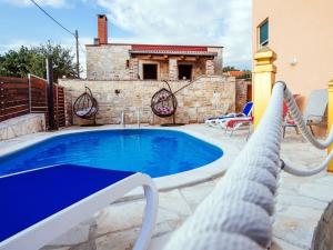 uma piscina com um baloiço de corda e uma casa em Splendid Holiday Home in Jasenice em Maslenica