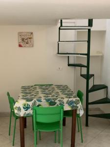 una sala da pranzo con un tavolo e sedie verdi di DEA PARTHENOPE a Napoli