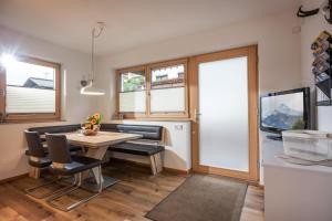 a living room with a table and chairs and a tv at Apart Alpenrose in Schwendau