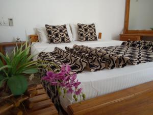 uma cama com lençóis pretos e brancos e flores roxas em Hotel Gayan's em Udawalawe